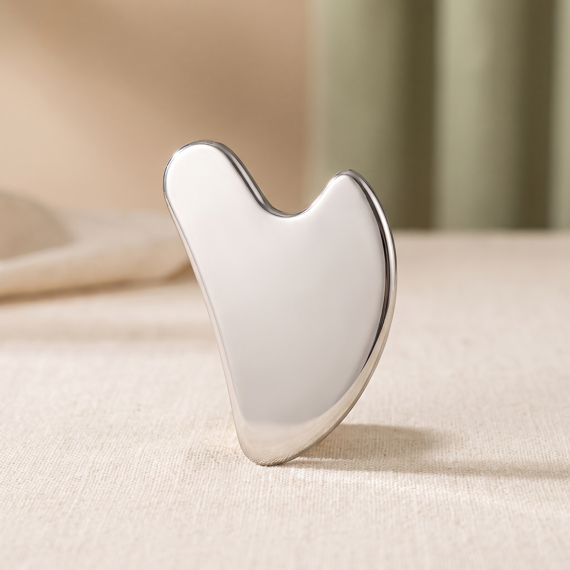 Senvè Gua Sha stainless steel tool on cream linen
