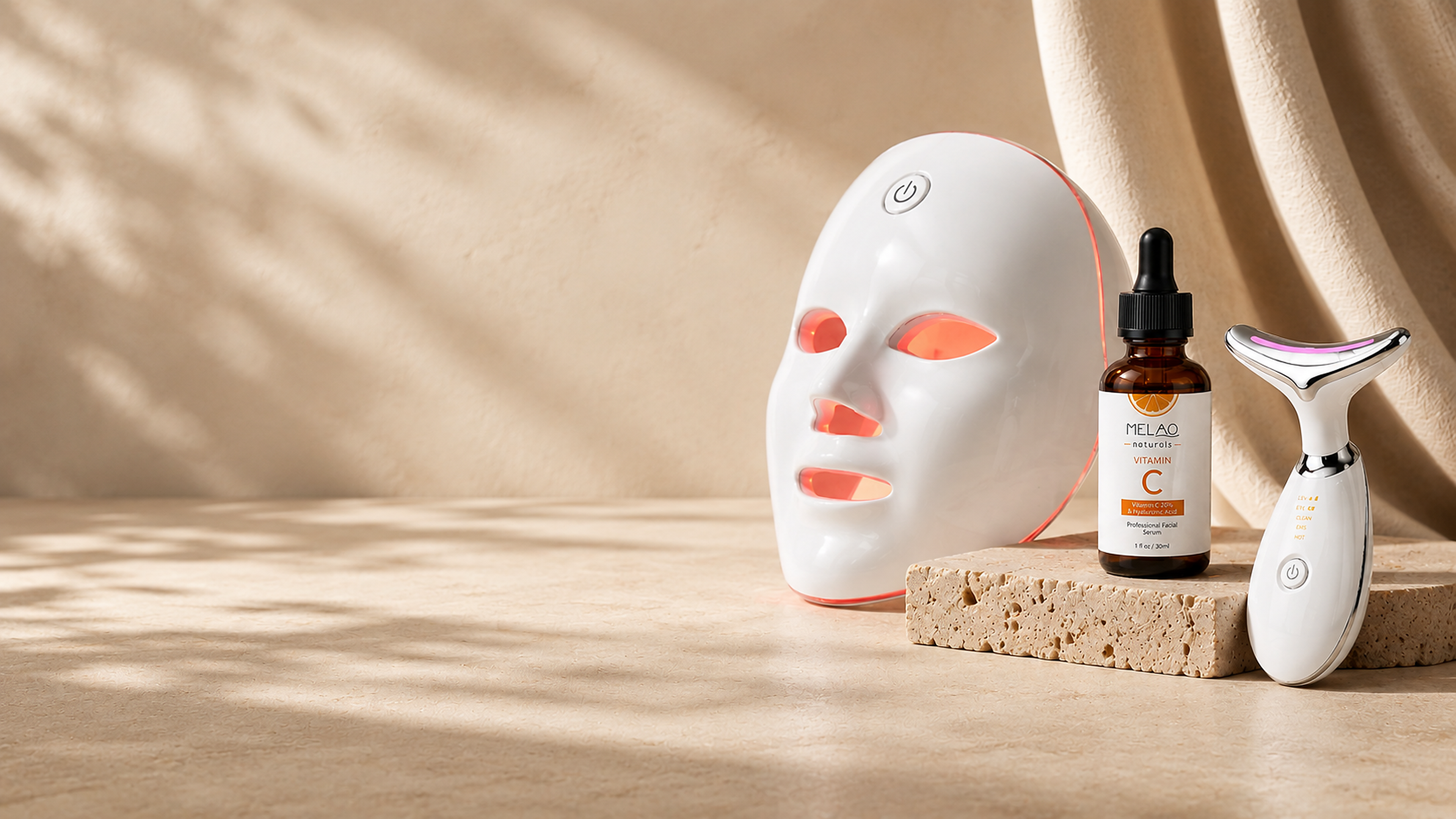 SENVÈ 7-Color LED Mask, Vitamin C Serum, and Neck Massager on a wide stone surface with negative space