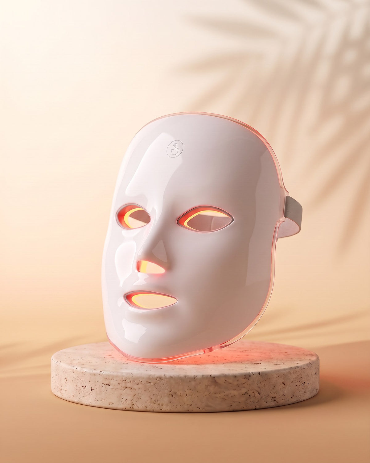 SENVÈ LED Light Therapy Mask lit in red on a travertine plinth
